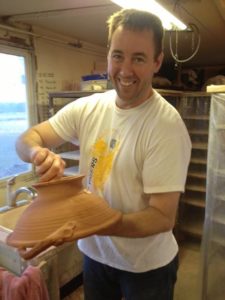photo of a man holding a pottery bowl upside down and posing 